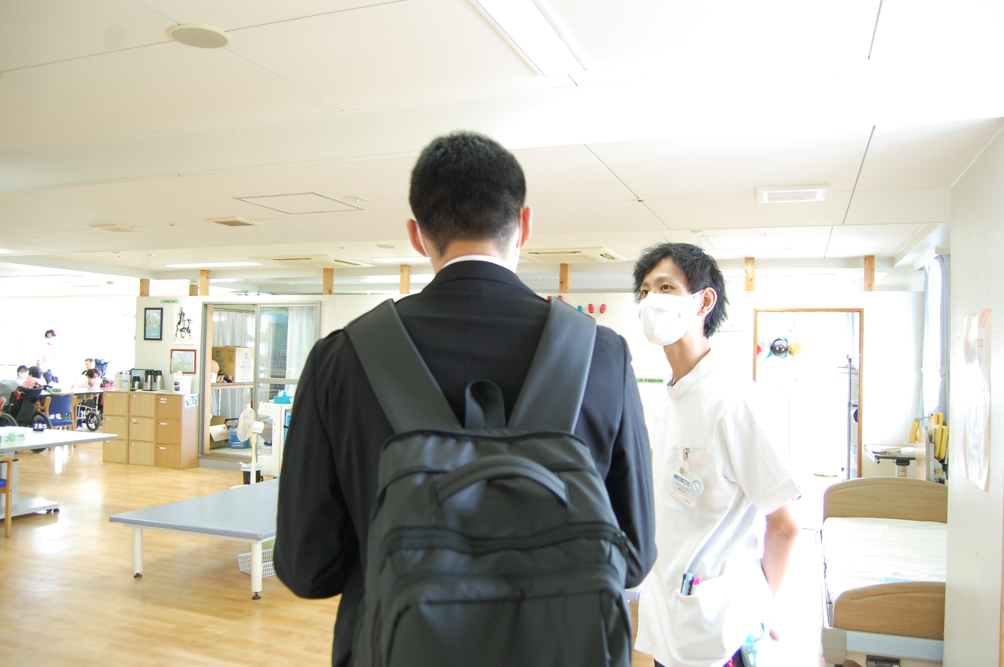 学校の就職担当者に作業療法室などの院内施設を案内する作業療法士
